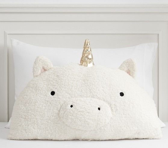 a white pillow with a gold unicorn head on it's side, sitting on top of a bed