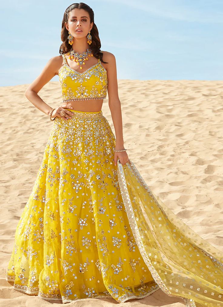 Bloom like a sunflower in our Yellow Mirror Embroidered Organza Lehenga! Adorned with sequin & mirror hand work embellishments around the hem and the neckline.