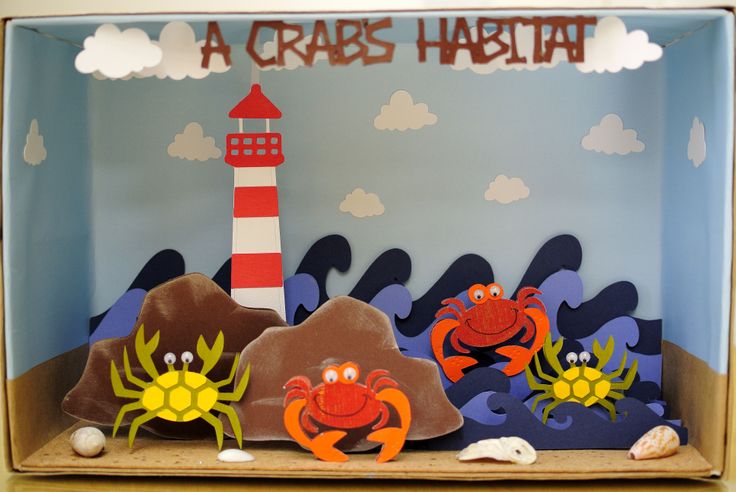 an ocean scene made out of cardboard with crabs and a lighthouse on the rocks in the background