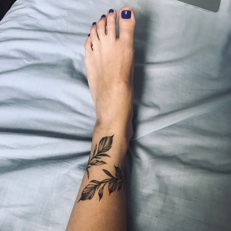 a woman's foot with a leaf tattoo on it