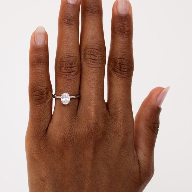 a woman's hand with an engagement ring on her left hand, against a white background