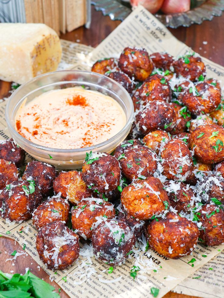 a pile of fried food sitting on top of a table next to a bowl of dipping sauce