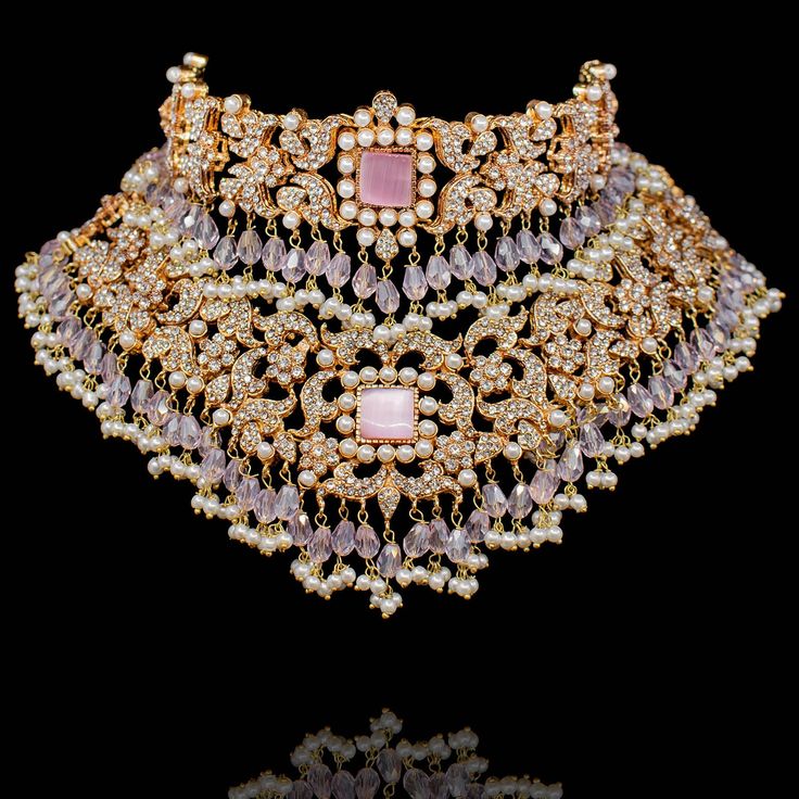 Our endeavour to re-express Mughal's history of jewels and their designs! A classic layout of CZ stones strung in harmony with pink beads. The set includes a choker paired with a necklace, a matching maang teekah, a jhoomar and a pair of beautiful jhumkey earrings. Approximate earrings length is 3.5". Gold-plated on high-quality brass as base metal. In-stock & ready-to-ship. *Please Note: We use faux stones and beads in all of our jewelry. Luxury Pink Kundan Necklace, Luxury Ornate Kundan Necklace, Ornate Gold Kundan Jewelry Sets, Luxury Traditional Brass Bridal Necklace, Ornate Brass Kundan Necklace For Wedding, Faux Stone, Pink Beads, Cz Stone, Base Metal