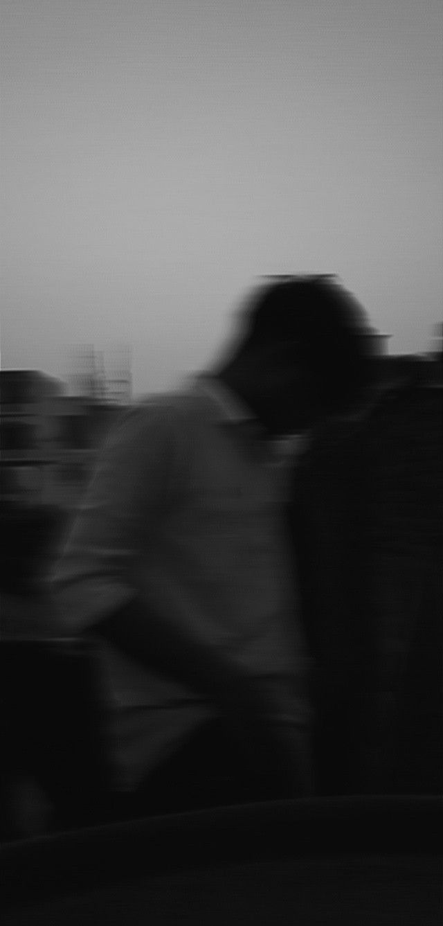 black and white photograph of two people sitting on a bench in front of the city skyline