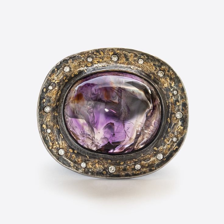 Designed by Michael Endlich Handmade by our workshop Argentium silver ring with natural diamond Gem: bicolor amethyst cabochon, 81.16ct Details: 1 secret round brilliant diamond, 0.19ct Accents: 16 round brilliant diamonds, 0.46ctw Size: 10.25 Scale: approx. 40.7mm x 46.7mm Unique Polished Gemstones For Formal Occasions, Unique Formal Gemstones With Polished Finish, Unique Oval Amethyst Ring With Gemstone Accents, Luxury Oval Diamond Ring With Stone Setting, Unique Formal Polished Gemstones, Unique Oval Amethyst Ring For Formal Occasions, Exquisite Amethyst Rings With Gemstone Accents, Oval Amethyst Gemstone With Stone Setting, Luxury Rings With Gemstone Accents In Oval Cabochon