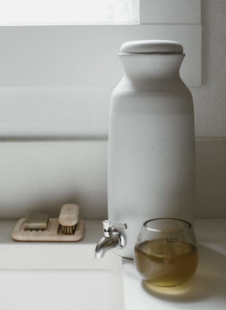 a white bottle sitting on top of a counter next to a glass and toothbrush