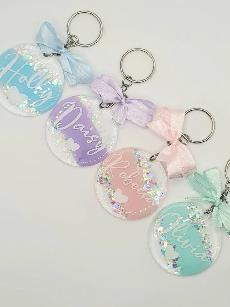 four keychains with different designs and colors on them, one has a bow