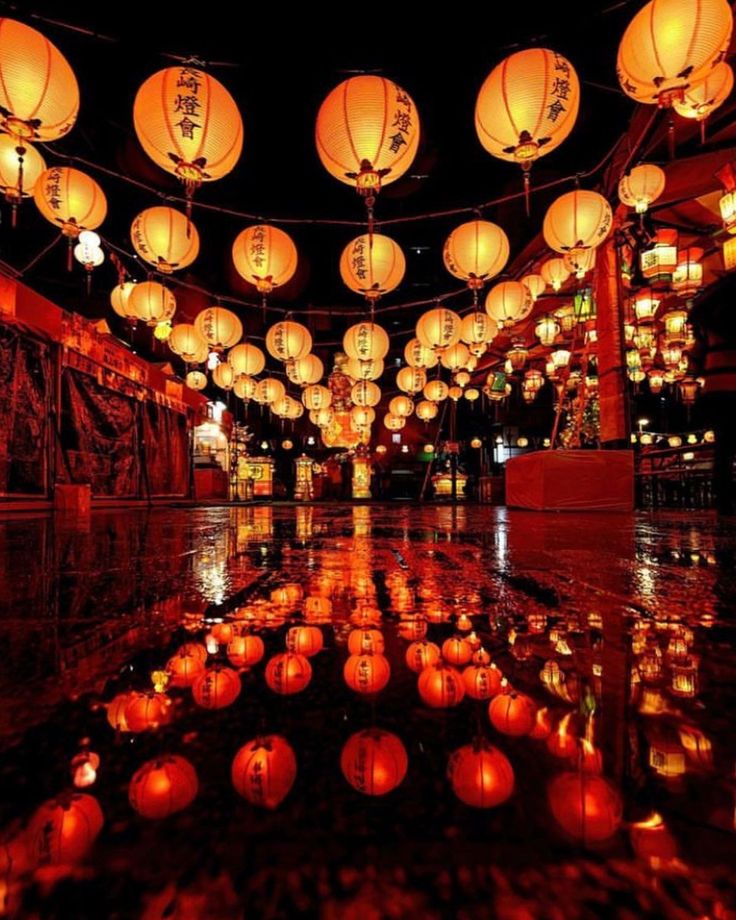 many lanterns are lit up in the dark with water reflecting them on the floor and around them