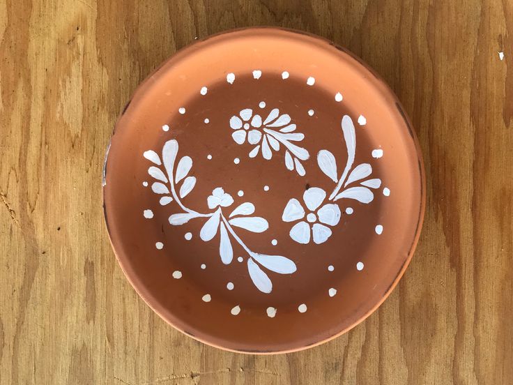 a brown bowl with white flowers painted on it