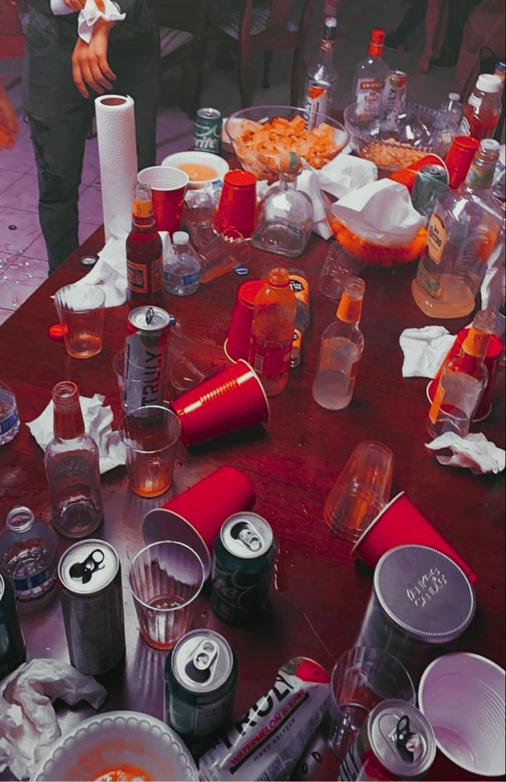 the table is covered with many empty cups and food items, including sodas, donuts, and pizza