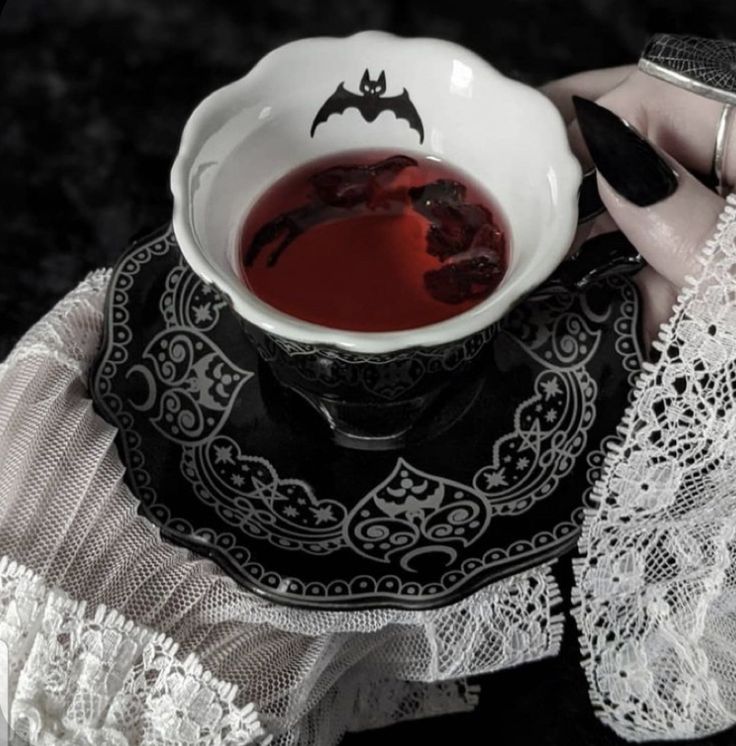 a woman is holding a tea cup with red liquid in it