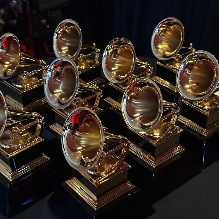 several golden and silver trophies sitting on top of each other in front of a black background