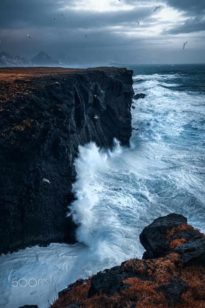 an ocean cliff with waves crashing against it