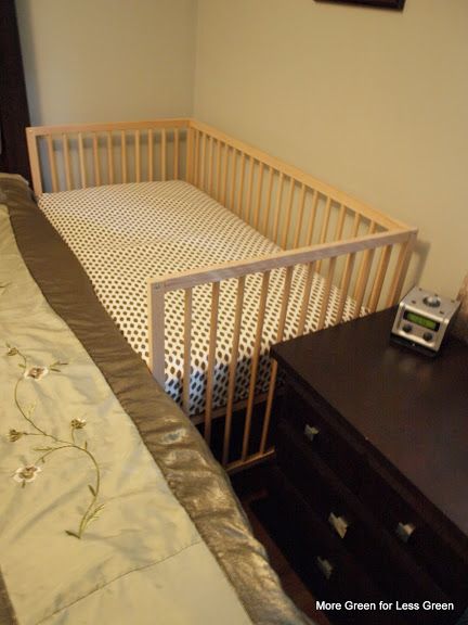 a baby crib next to a night stand and dresser