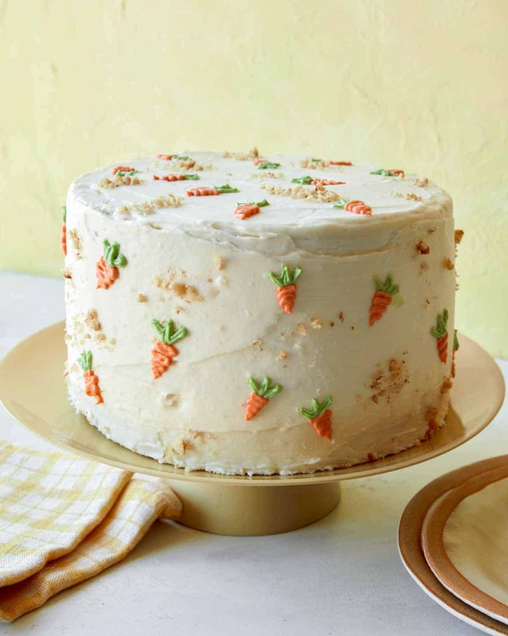 a carrot cake with frosting and sprinkles on a gold platter