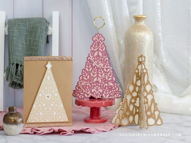 three small christmas trees sitting on top of a table next to a vase and other decorations