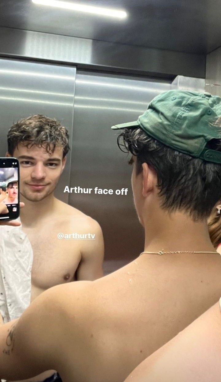 the man is taking a selfie in the mirror with his cell phone while wearing a green hat