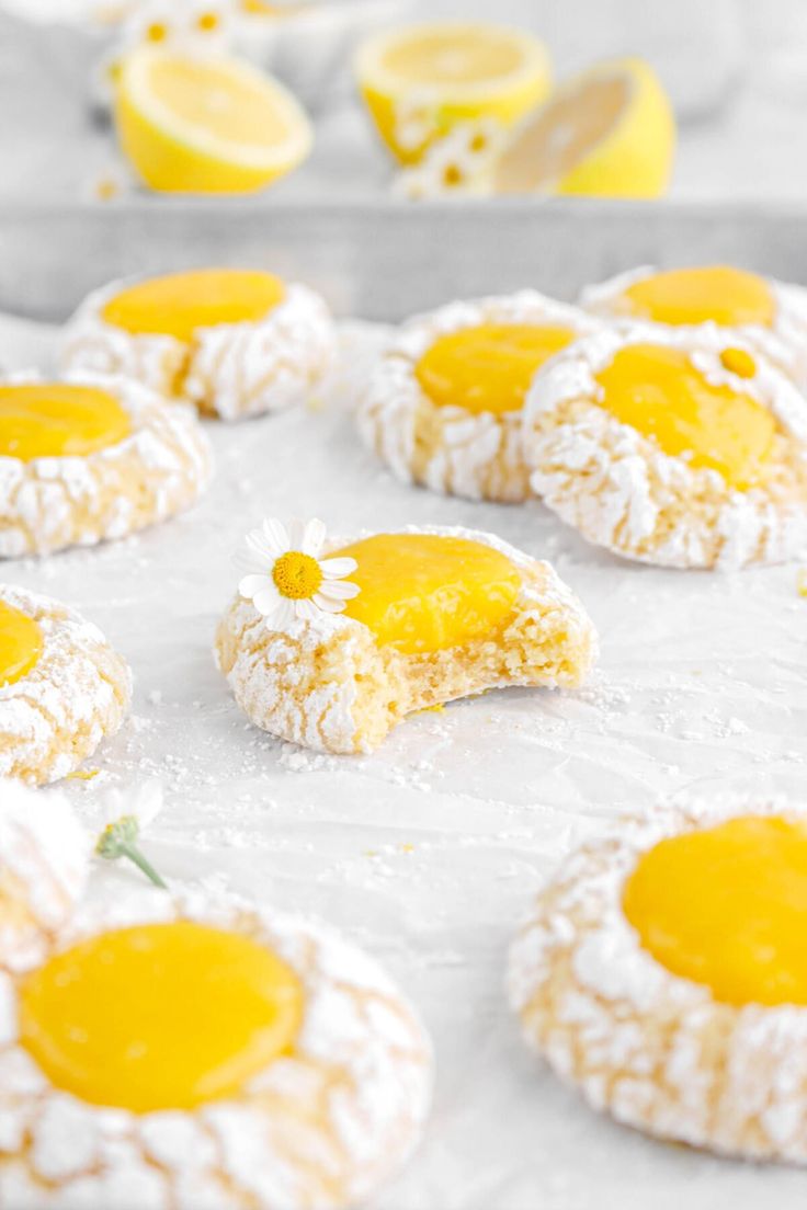 lemon cookies are covered in powdered sugar and decorated with daisies on a baking sheet