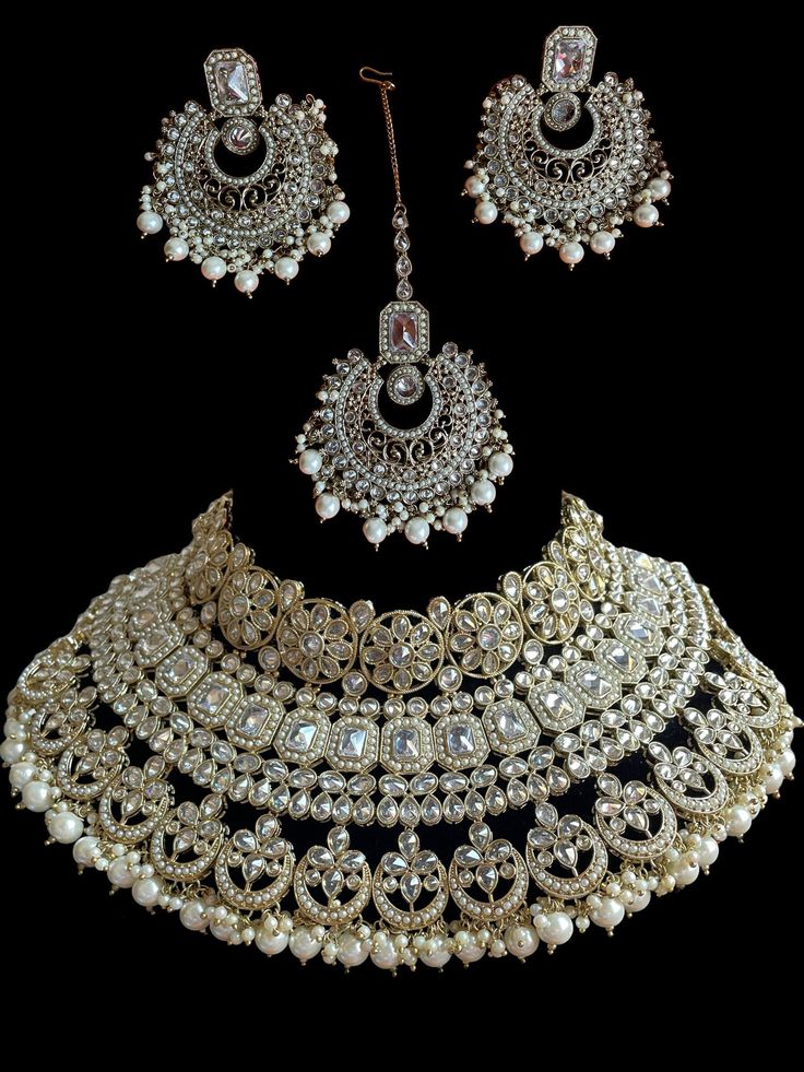 This bridal set comes in a gorgeous white beads and bronze gold plating. The set is lightweight and can easily be worn separately for a lighter and simple look. The finishing is done in gold and is completely handmade with intricate work. Only one piece in stock! White Kundan Necklaces For Marriage, Traditional White Necklace For Marriage, White Festive Necklace For Marriage, Festive White Necklace For Marriage, Festive White Wedding Necklace, Gold Kundan Bridal Accessories For Reception, Gold Hand-set Bridal Accessories For Reception, Gold Hand Set Bridal Accessories For Reception, Gold Chandbali Bridal Accessories Hand Set