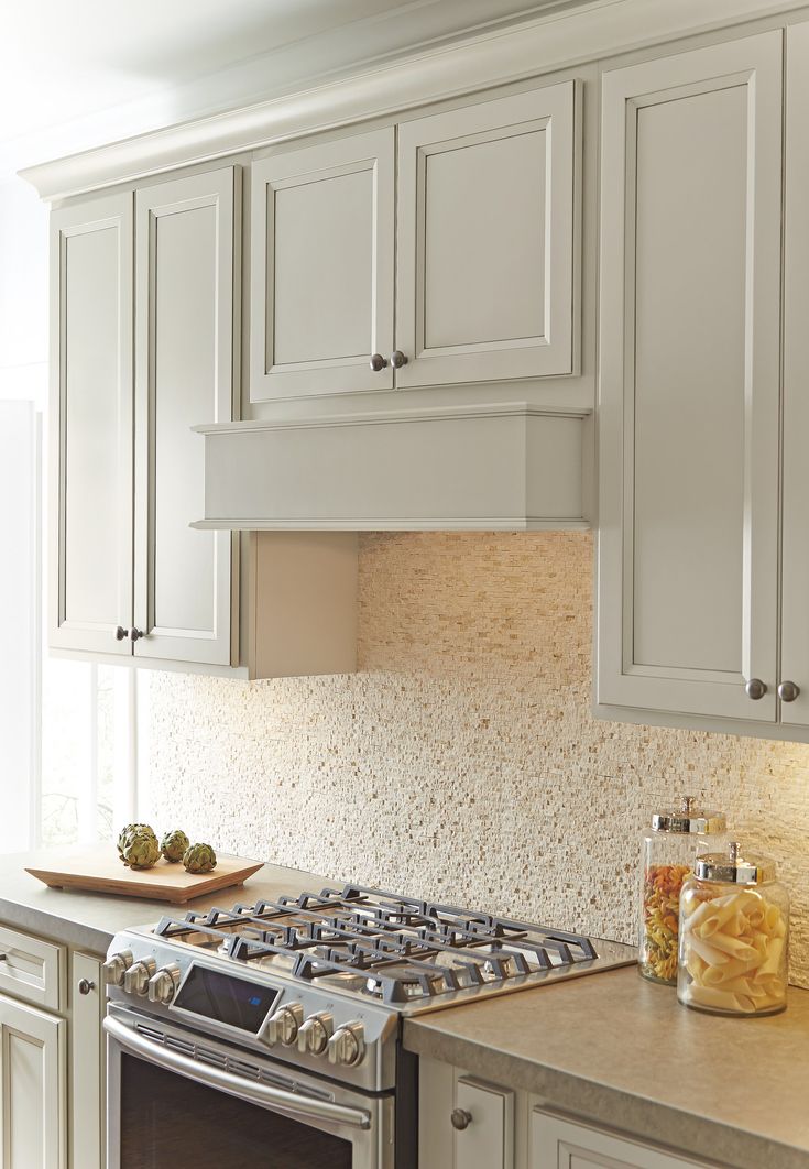 a stove top oven sitting inside of a kitchen next to white cabinets and counter tops