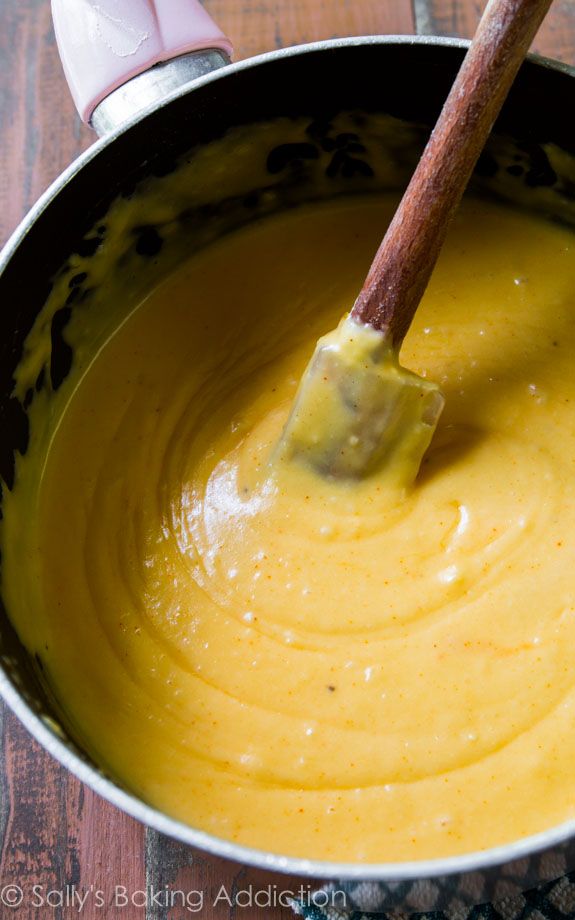 a wooden spatula in a pan filled with yellow sauce