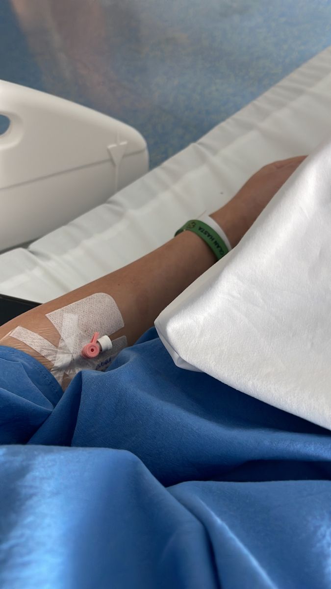 a person laying in a hospital bed with an iv attached to their arm and hand