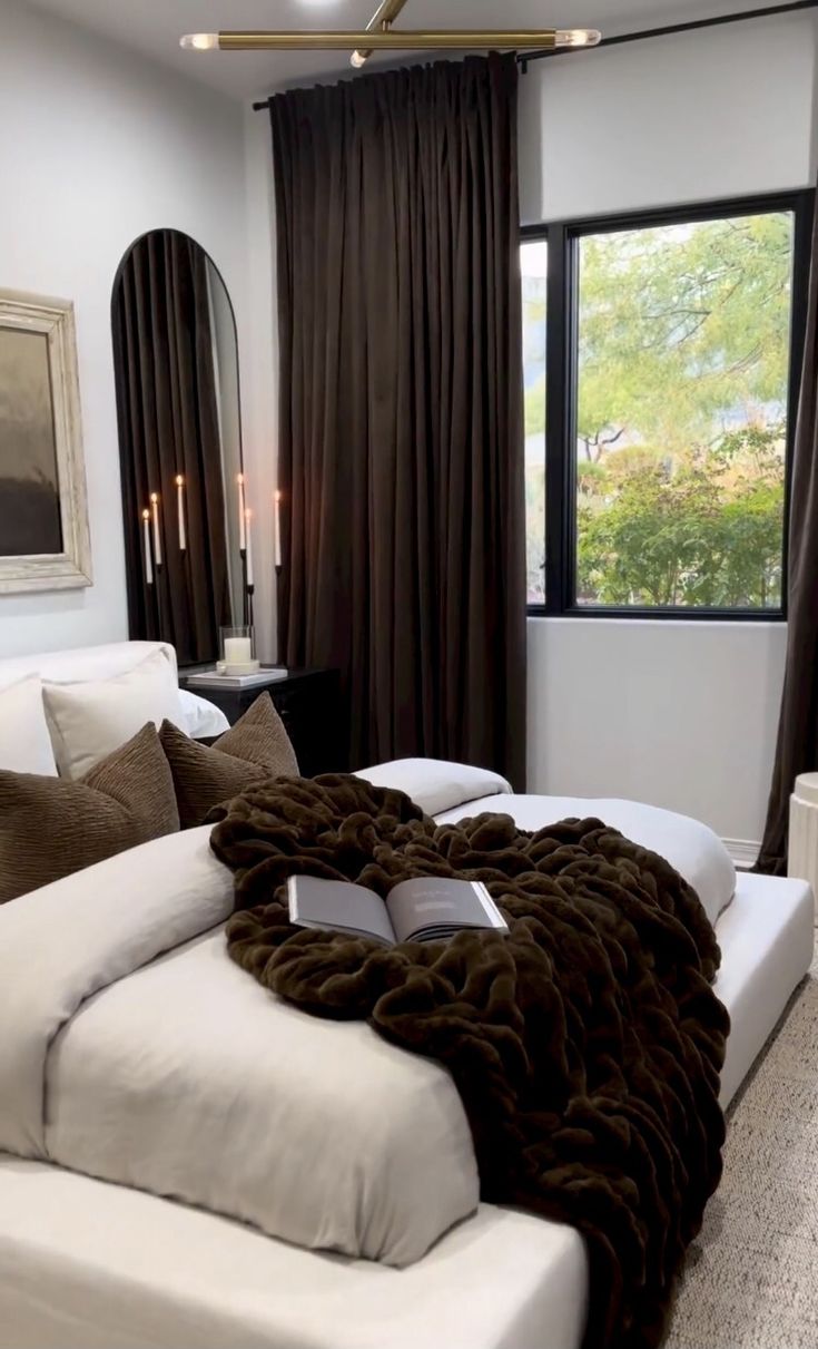 a large white bed sitting in a bedroom next to a window with curtains on it