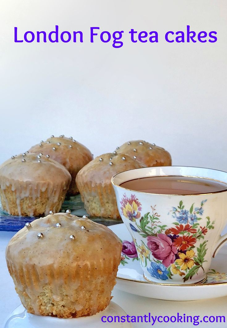 three muffins on a plate next to a cup of tea and saucer