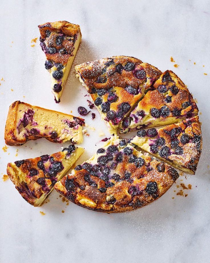 a blueberry cheesecake cut into slices on a white surface with one slice missing