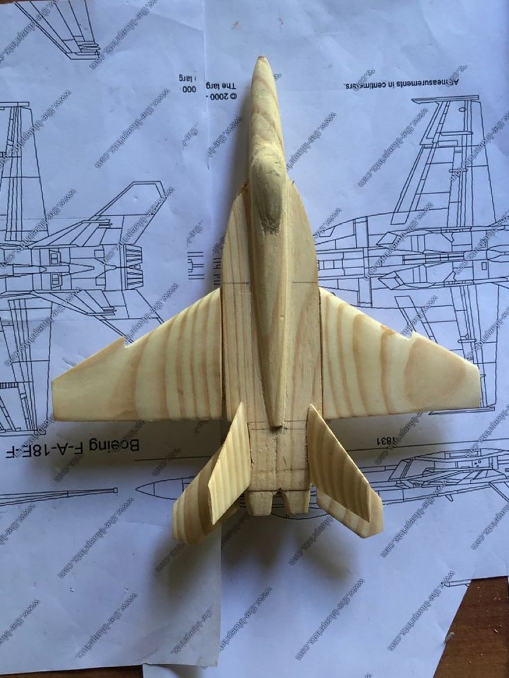 a wooden model of a fighter jet sitting on top of paper