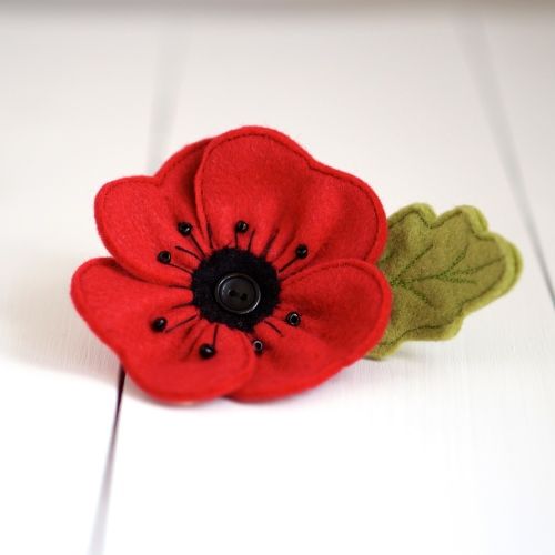 a red flower with black center sitting on top of a white table