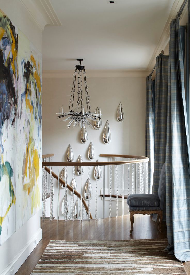 a dining room table and chairs in front of a painting on the wall next to a chandelier