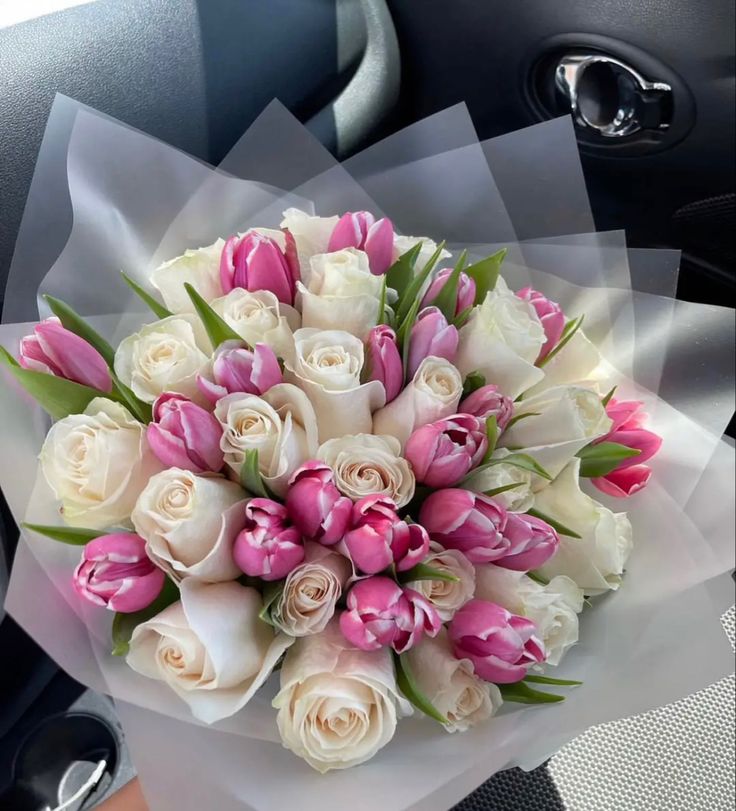 a bouquet of pink and white flowers sitting on top of a car door sill