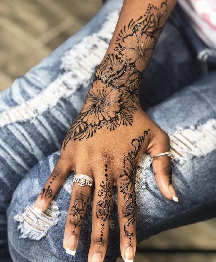 a woman's hand with hennap and flowers on her left hand, sitting on the ground