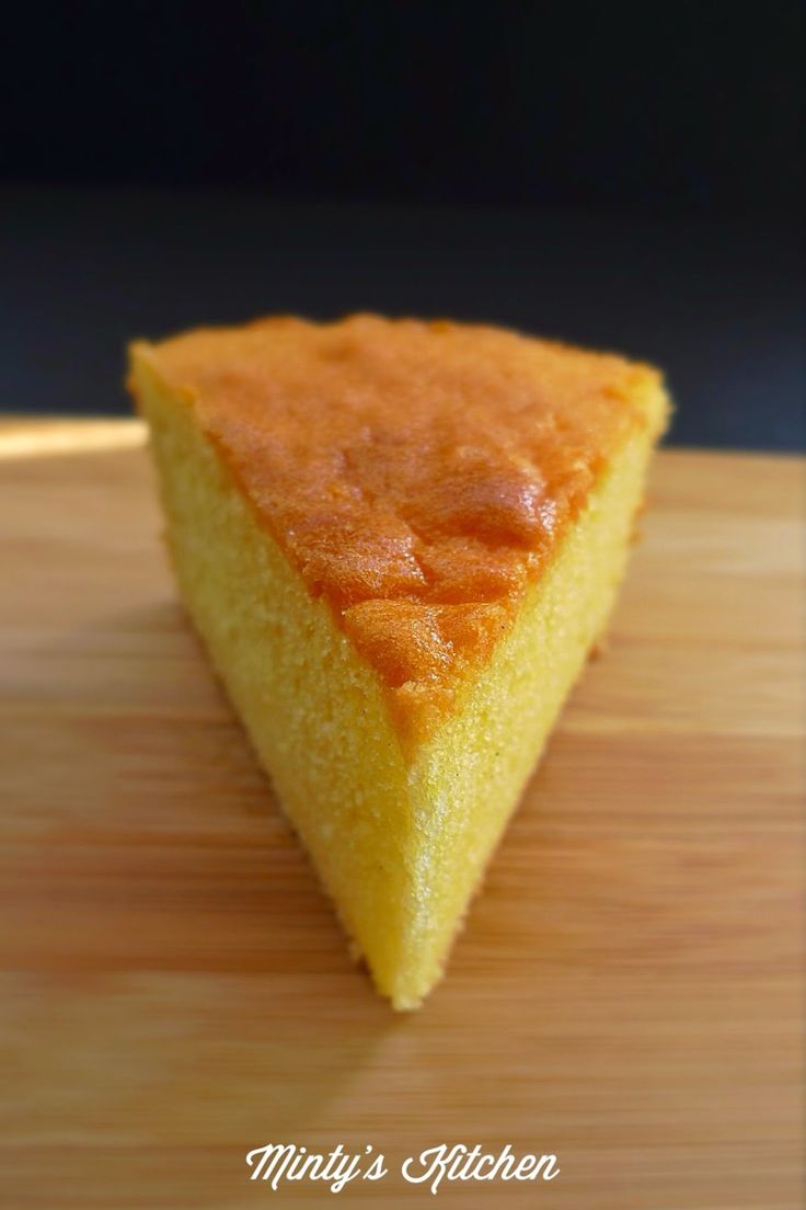 a piece of yellow cake sitting on top of a wooden cutting board