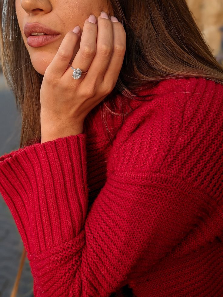 a woman wearing a red sweater and diamond ring