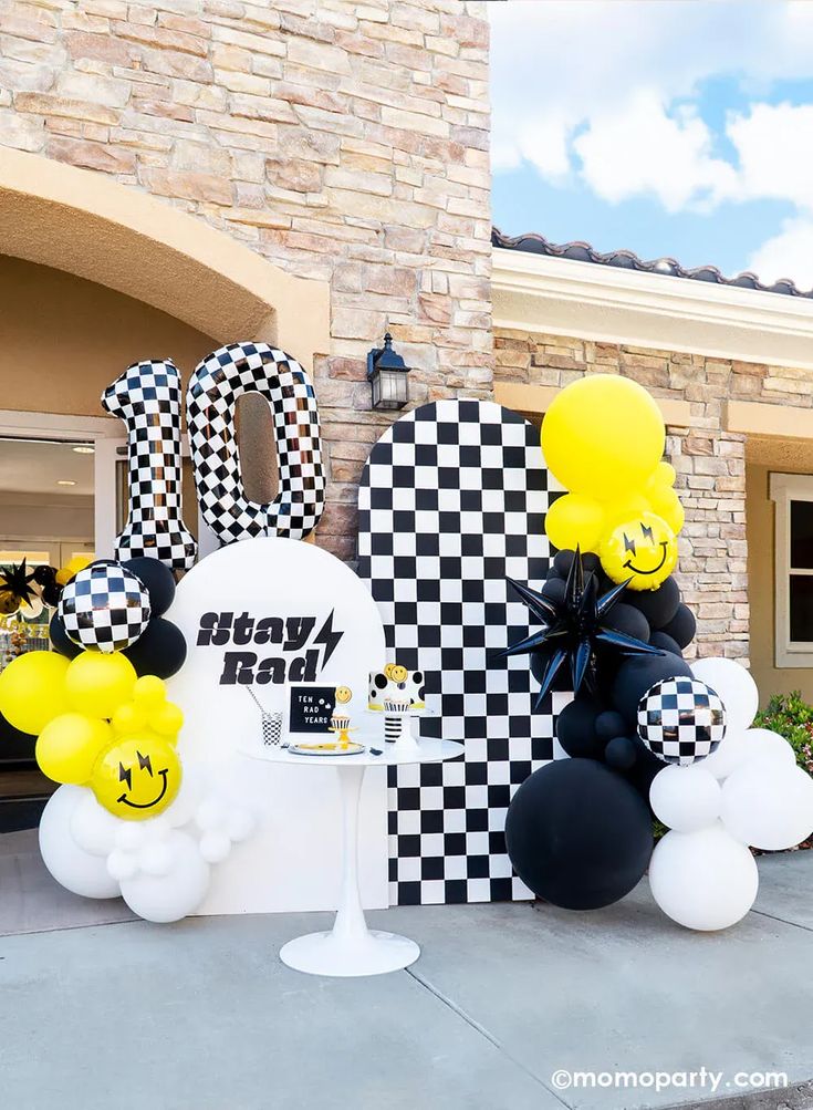 some balloons are sitting in front of a building with checkered walls and black and white decorations