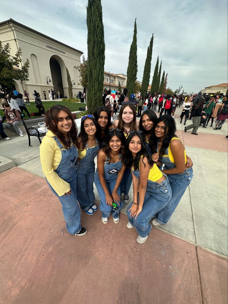 a group of young women standing next to each other in front of a building with trees