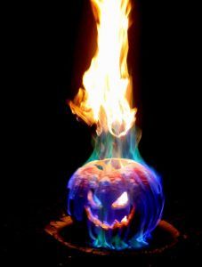 a lit pumpkin sitting on top of a fire pit with flames coming out of it