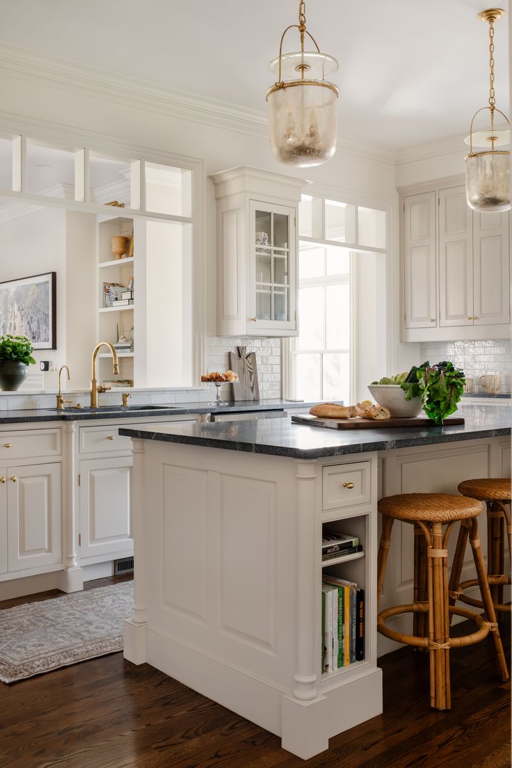 a kitchen with white cabinets and an island in front of the counter top is surrounded by stools