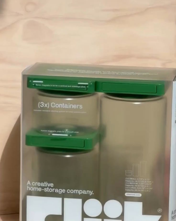 two green containers sitting on top of a wooden table next to a box with the lid open