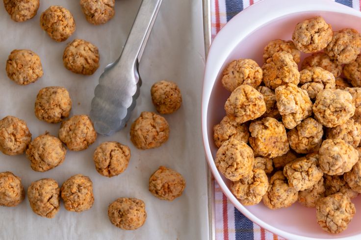 a white bowl filled with oatmeal cookies next to a spoon and napkin