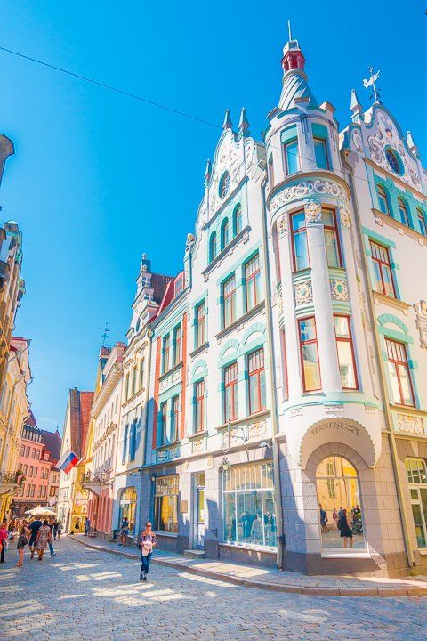 people are walking down the street in front of some old buildings on a sunny day