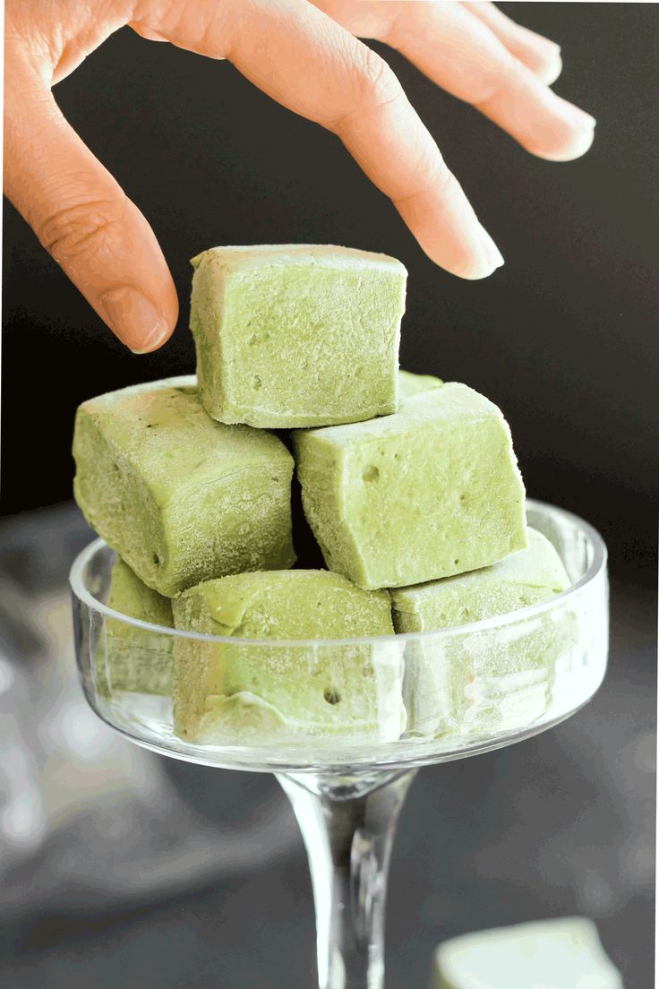 a person reaching for some food on top of a glass bowl with ice cubes in it