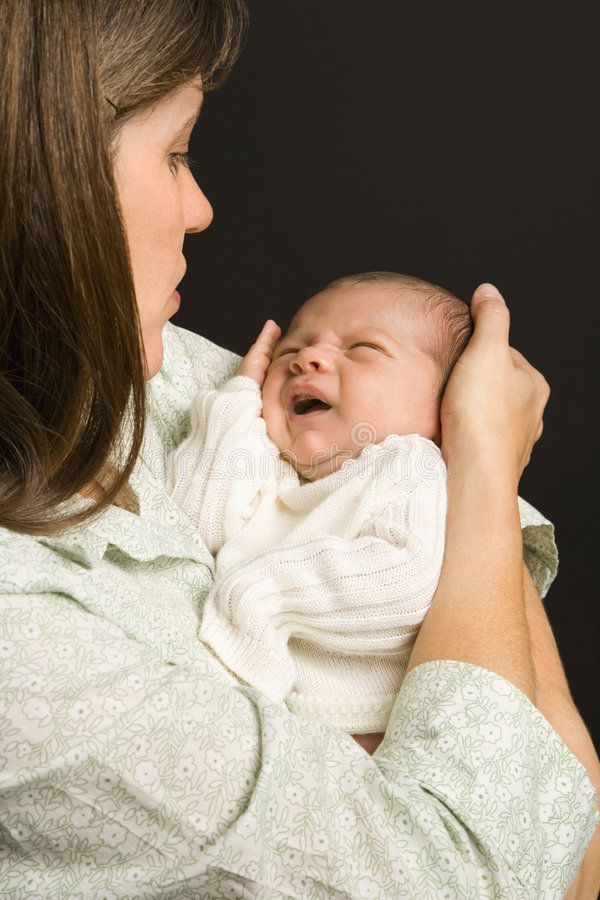 a woman holding a baby in her arms and smiling at it's mother stock photos