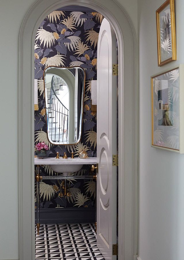 an archway leading into a bathroom with wallpaper and mirror on the door way to another room