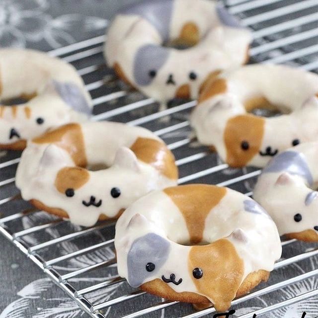 some donuts with white frosting and brown bears on them sitting on a cooling rack