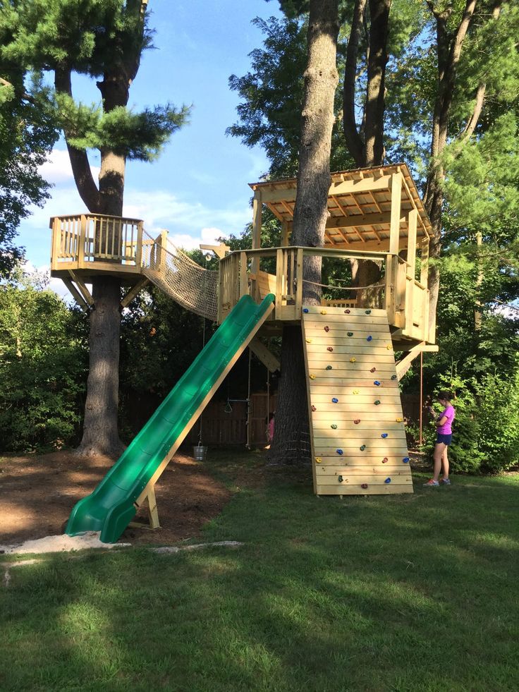 a child's play area with a slide and tree house in the back ground