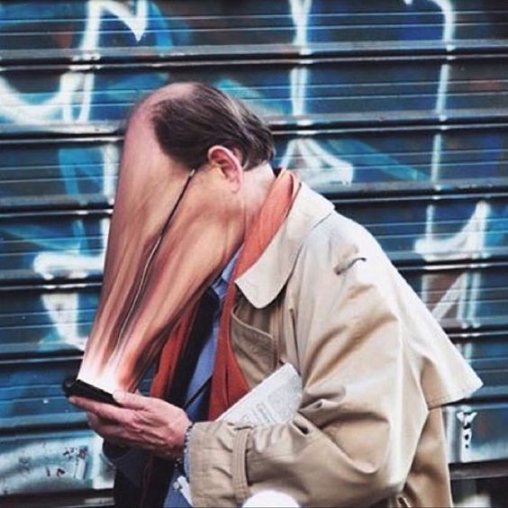 a man with his face covered in hair and holding a cell phone next to graffiti