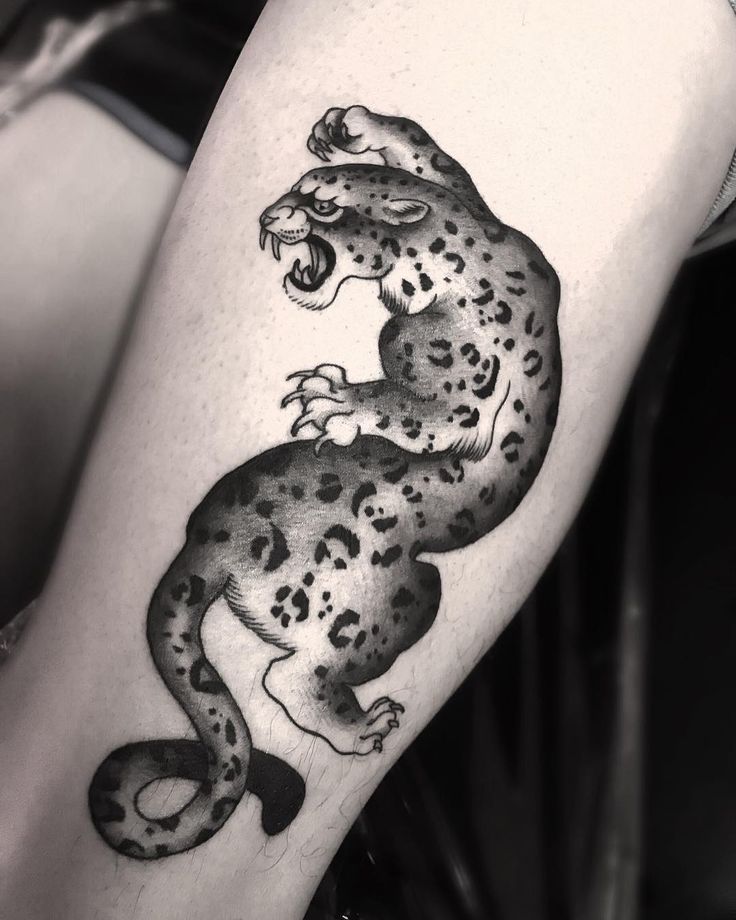 a black and white tattoo of a leopard on the leg